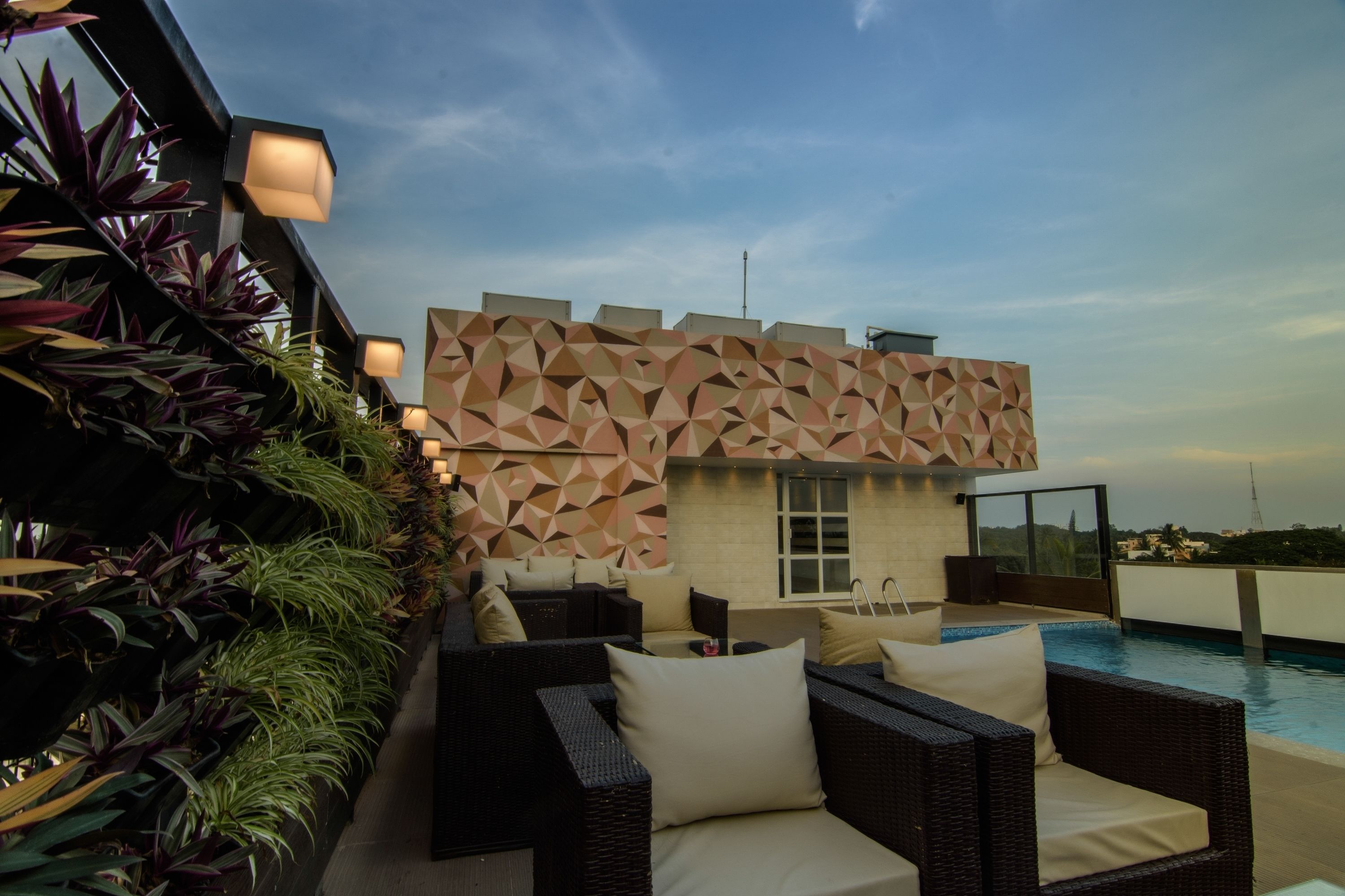 A rooftop pool area with outdoor seating and a geometric wall design.