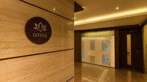 A polished marble wall with a 'LOTUS' sign, a patterned glass door, and a modern interior design. - Roopa Elite (Mysore)