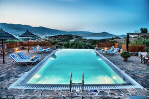 Una piscina al aire libre, sombrillas, sillones reclinables de piscina