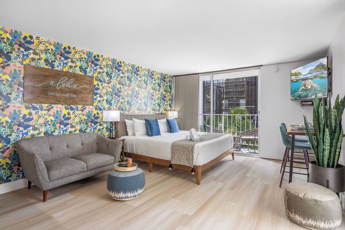 A modern bedroom with a bed, a sofa, a coffee table, and a large window.