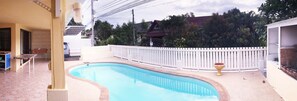 Una piscina con recinzione bianca, un tavolino e una sedia.