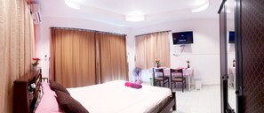 Una camera d'albergo con un letto, una scrivania, una sedia, una televisione e tende.