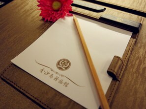 Ein Dokument mit einem Logo und Text, einem Bleistift und einer roten Blume auf einer Holzoberfläche.