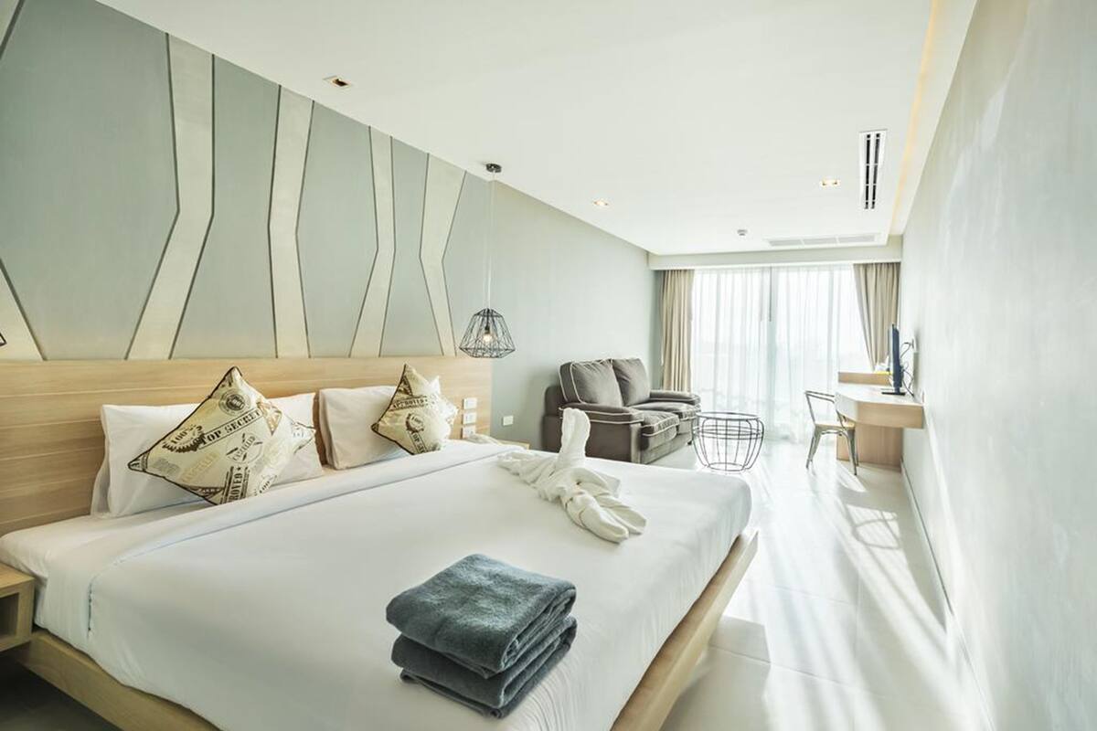 Una habitación de hotel moderna con una cama grande, un escritorio y una silla.