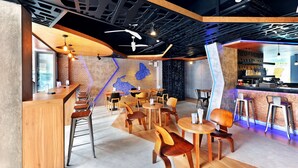 A modern cafe with wooden furniture, a bar area, and a unique ceiling design. - Ratana Patong Beach Hotel by Shanaya (Patong)