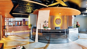 A reception area with a curved desk, a logo, and a modern interior design. - Ratana Patong Beach Hotel by Shanaya (Patong)