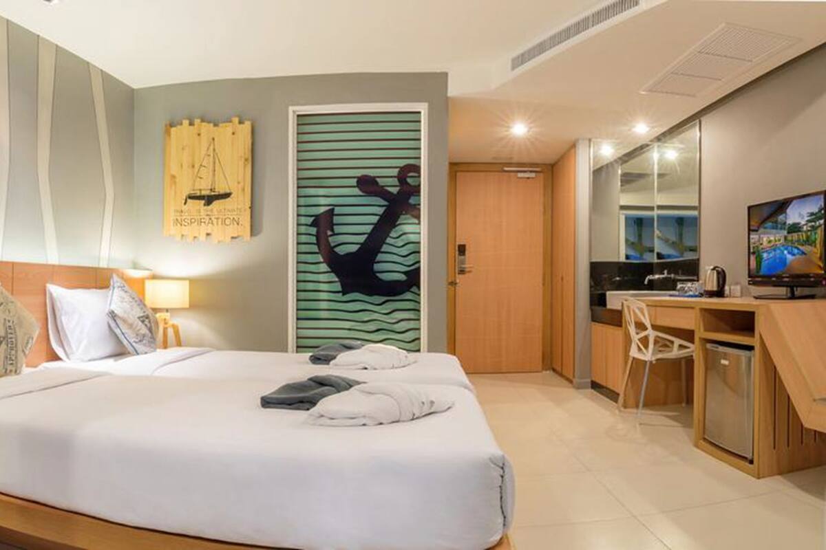 Una habitación de hotel con cama, mesita de noche, lámpara y escritorio con silla.