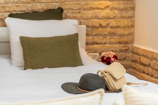 A bed with white bedding, a green pillow, and a woven bag on the side. - Grand Vista Boutique Hotel And Spa (Mevoot HaHermon)