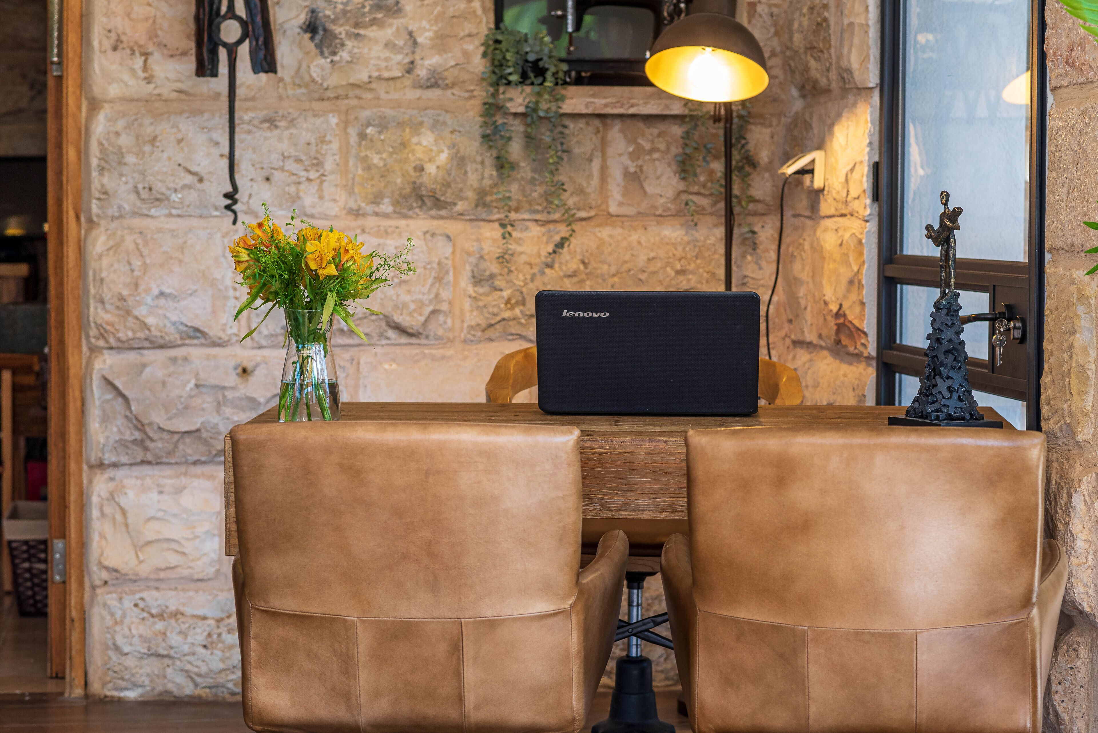 Ein Tisch mit einem Laptop, einer Blumenvase und einer Dekoration.