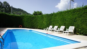 A rectangular swimming pool with a clear blue water surface, surrounded by a white pool deck. There are white lounge chairs aligned along the pool's edge. - Hotel la Planada (Ordino)