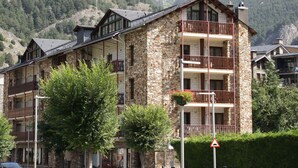 A multi-story stone building with balconies, surrounded by lush greenery and mountains. - Hotel la Planada (Ordino)