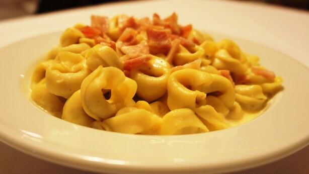 A plate of pasta with a creamy sauce and pieces of ham. - Hotel la Planada (Ordino)