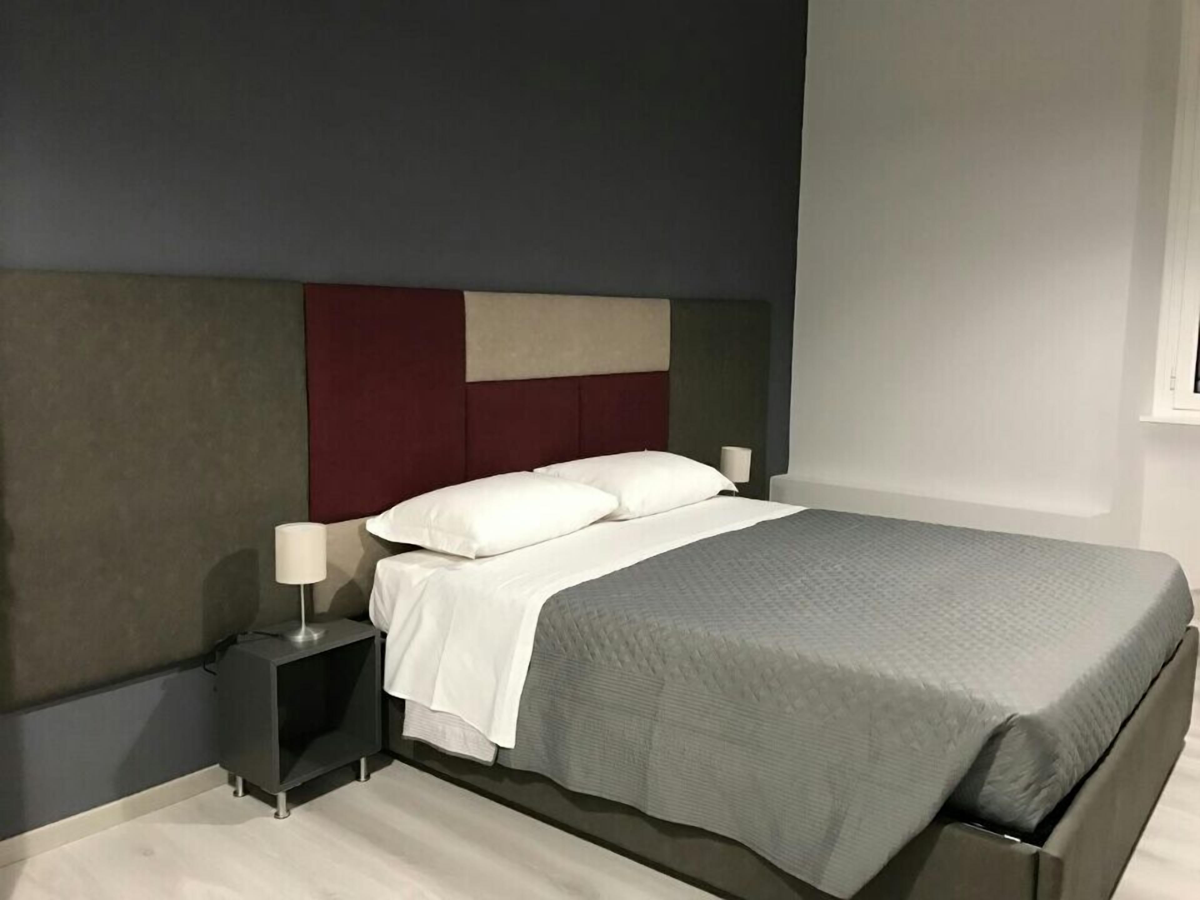 Una camera da letto moderna con un letto, un comodino e una lampada.