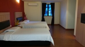 A hotel room with two beds, a window with curtains, an air conditioning unit, and a wooden floor. - Smart Hotel (Seremban)