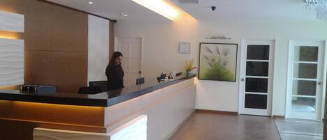 A reception area with a modern design, featuring a reception desk, a clock, and a framed artwork on the wall.