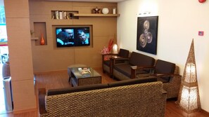 A living room with a sofa, a coffee table, and a TV mounted on the wall. - Smart Hotel (Seremban)
