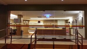 Et hotellets receptionsområde med en glasvæg, en receptionsdisk og en lysekrone.