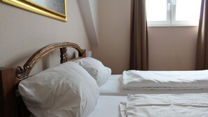 A double bed with white linens in a room with a wooden headboard, a framed picture on the wall, and a window with curtains. - Hotel Gardenia (Reiskirchen)