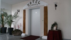 A hotel entrance with a sign reading "HOTEL GARDENIA," a marble floor, potted plants, and a red carpet. - Hotel Gardenia (Reiskirchen)
