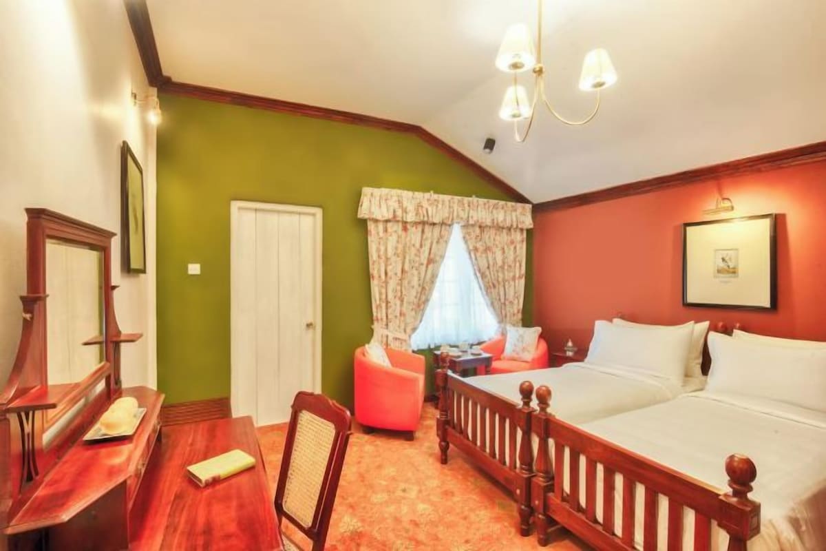 Un dormitorio con cama de madera, escritorio, silla, ventana con cortinas y puerta.