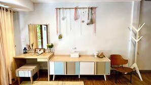 A room with a wooden desk, a chair, a bench, a colorful rug, and a wall-mounted plant arrangement. - Winnine Cozy Home (Bangkok)