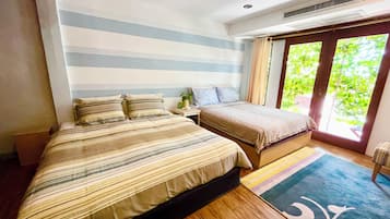 A bedroom with two beds, a window with curtains, and a wooden floor.