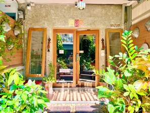 A hotel entrance with a tiled floor, wooden doors, and potted plants.