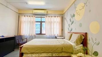 A bedroom with a bed, a desk, a chair, and a window with curtains.