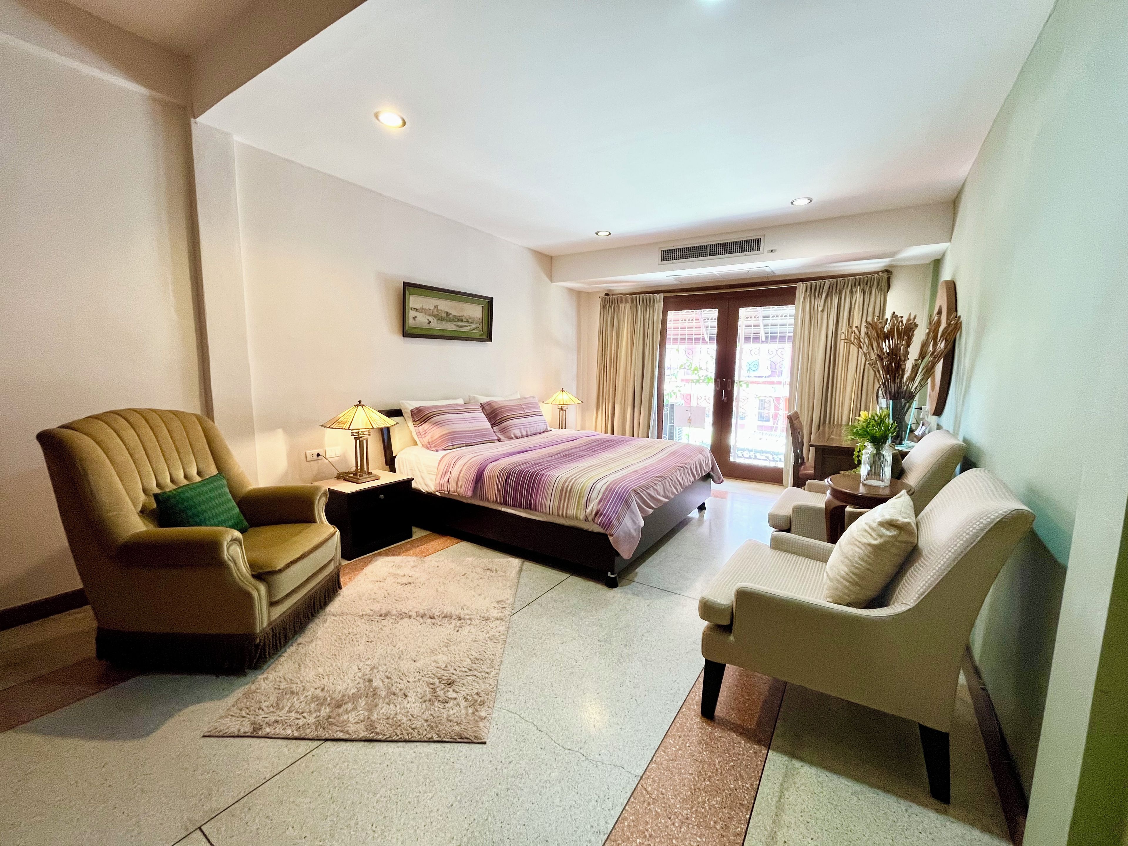 A hotel room with a bed, a chair, a desk, and a window.