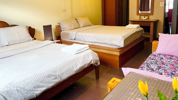 A hotel room with two beds, a wooden dresser, a mirror, and a small table with a floral tablecloth. - Winnine Cozy Home (Bangkok)