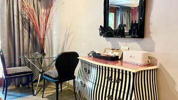 A room with a striped cabinet, a chair, a glass table, and a mirror on the wall.