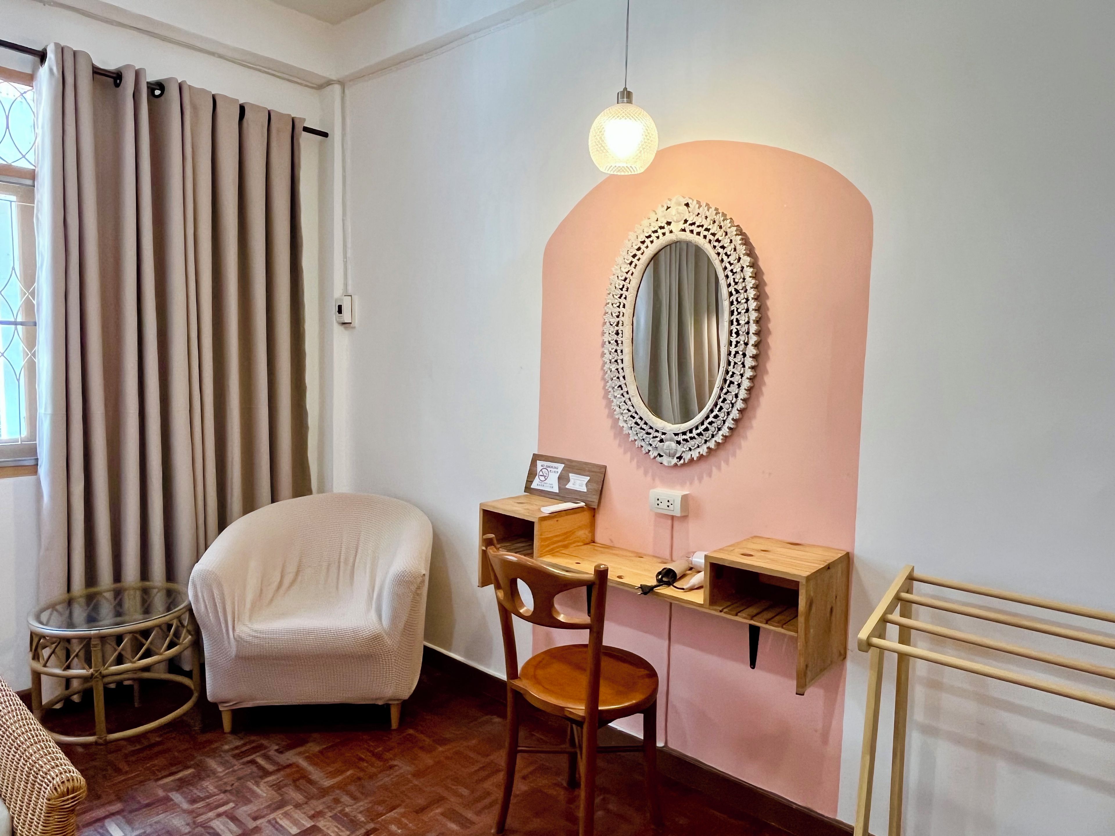 A room with a desk, chair, and a round mirror on the wall.