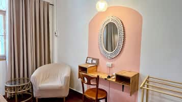 A room with a desk, chair, and a round mirror on the wall.