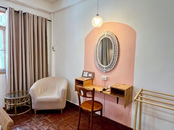 A room with a desk, chair, and a round mirror on the wall.