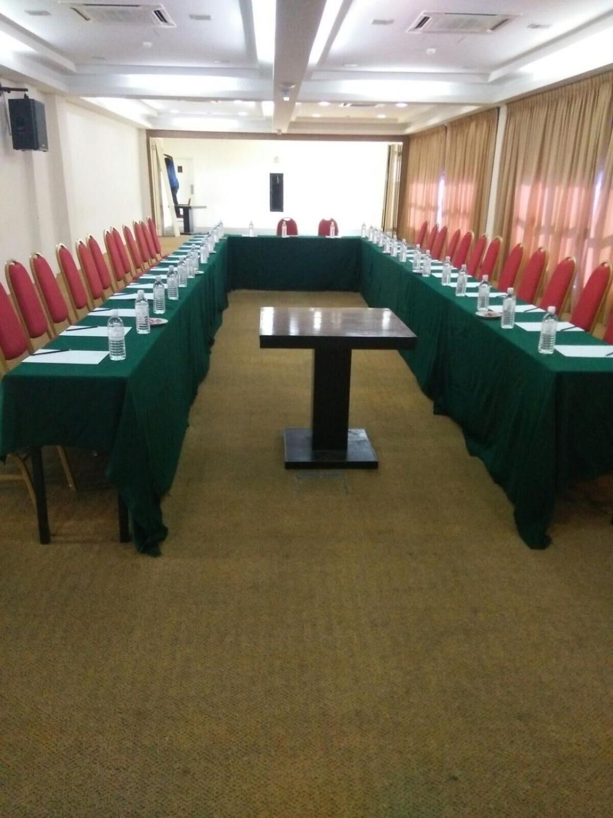 Ein Konferenzraum mit einem langen Tisch, roten Stühlen und Wasserflaschen.