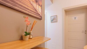 A wooden bench with a potted plant and reed diffuser. A door with a number sign is visible. - B&B Bentivogli (Bologna)