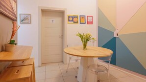 A room with a wooden table, a vase with flowers, and a door. There are framed certificates on the wall. - B&B Bentivogli (Bologna)