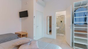 A bedroom with a bed, a TV, a wardrobe, and a bathroom visible through an open door. - B&B Bentivogli (Bologna)