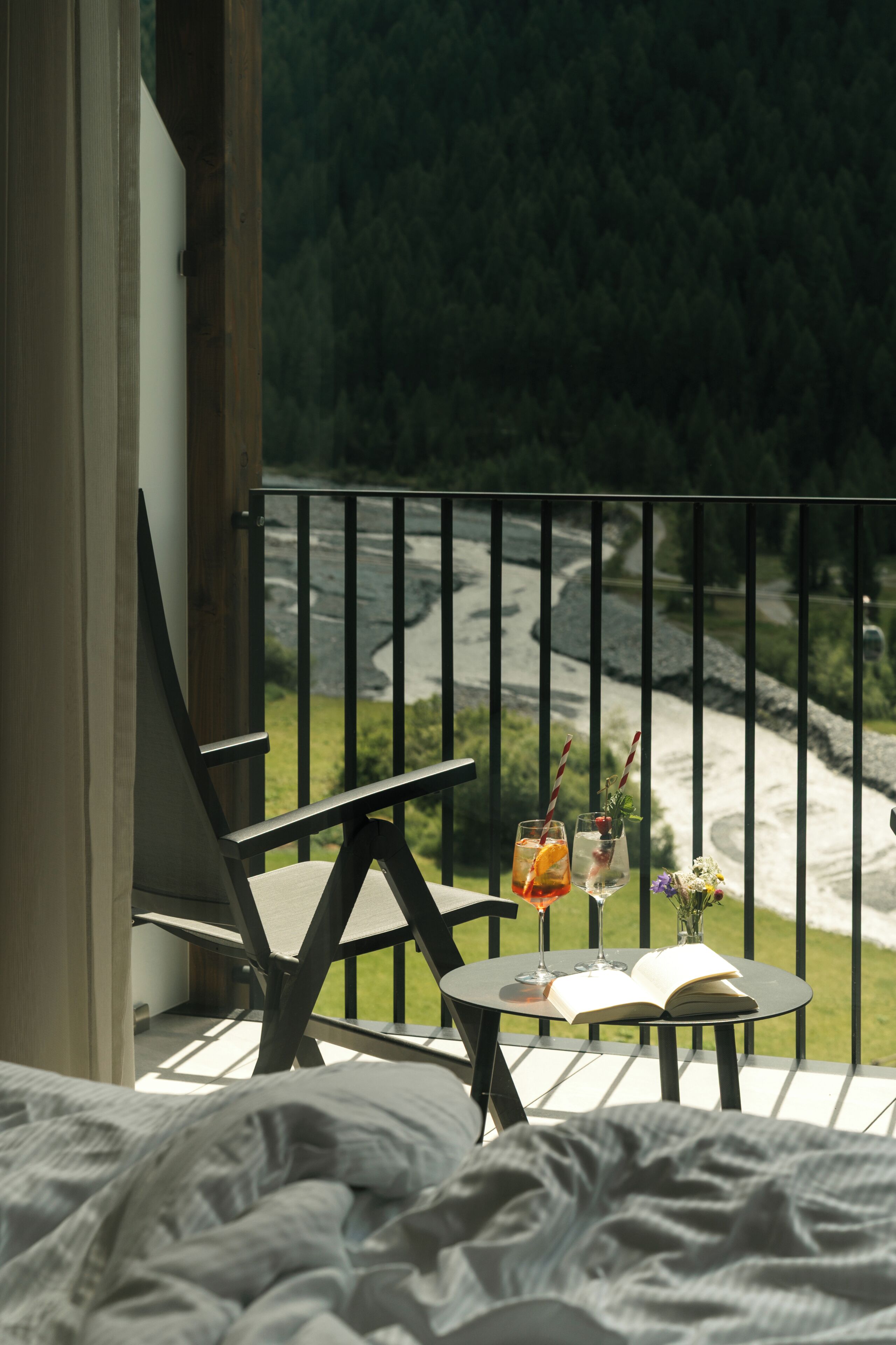 Ein Balkon mit Blick auf einen Fluss, ein Tisch mit Getränken und ein Stuhl.