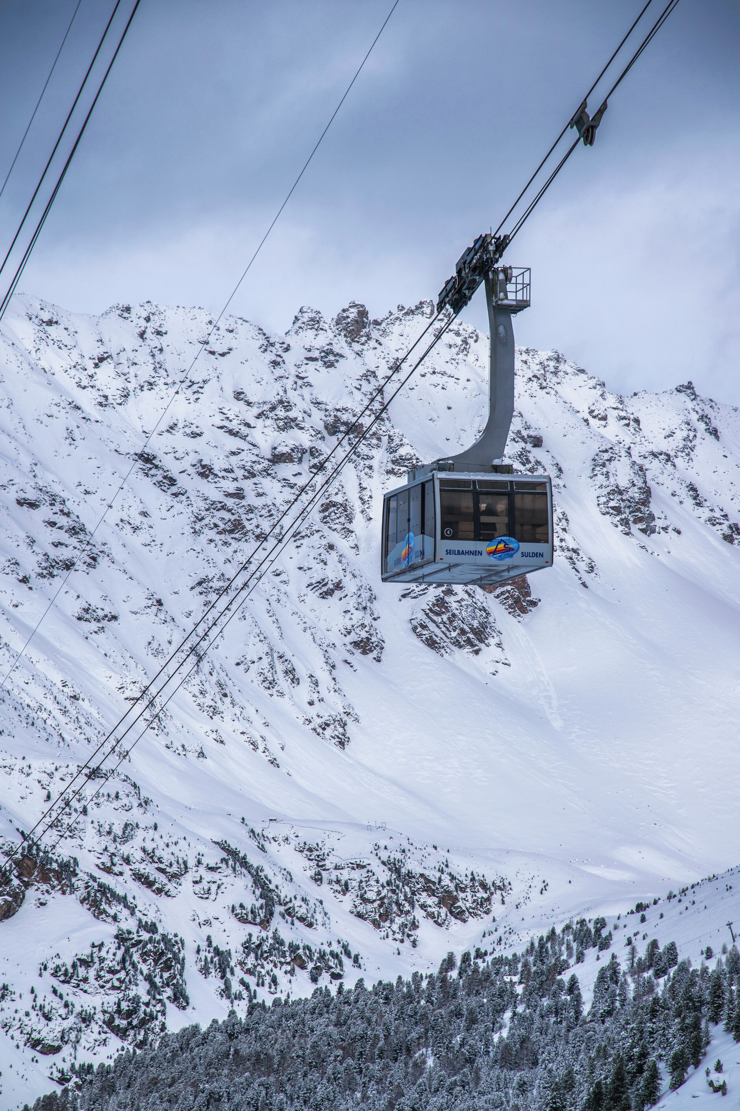 Un teleférico asciende una montaña nevada.