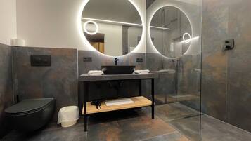 Un baño moderno con un espejo redondo, un lavabo y un inodoro.