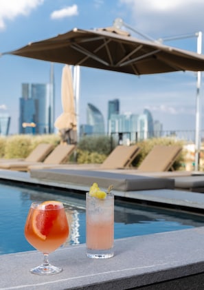 Relax by the pool with a refreshing drink in hand, surrounded by the vibrant cityscape.