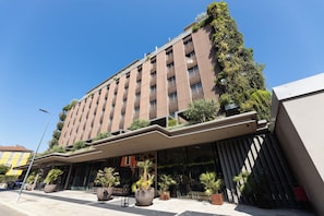 Stunning hotel facade with a unique wooden slat design and lush greenery.