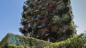Un edificio de varios pisos con amplios jardines verticales y balcones.