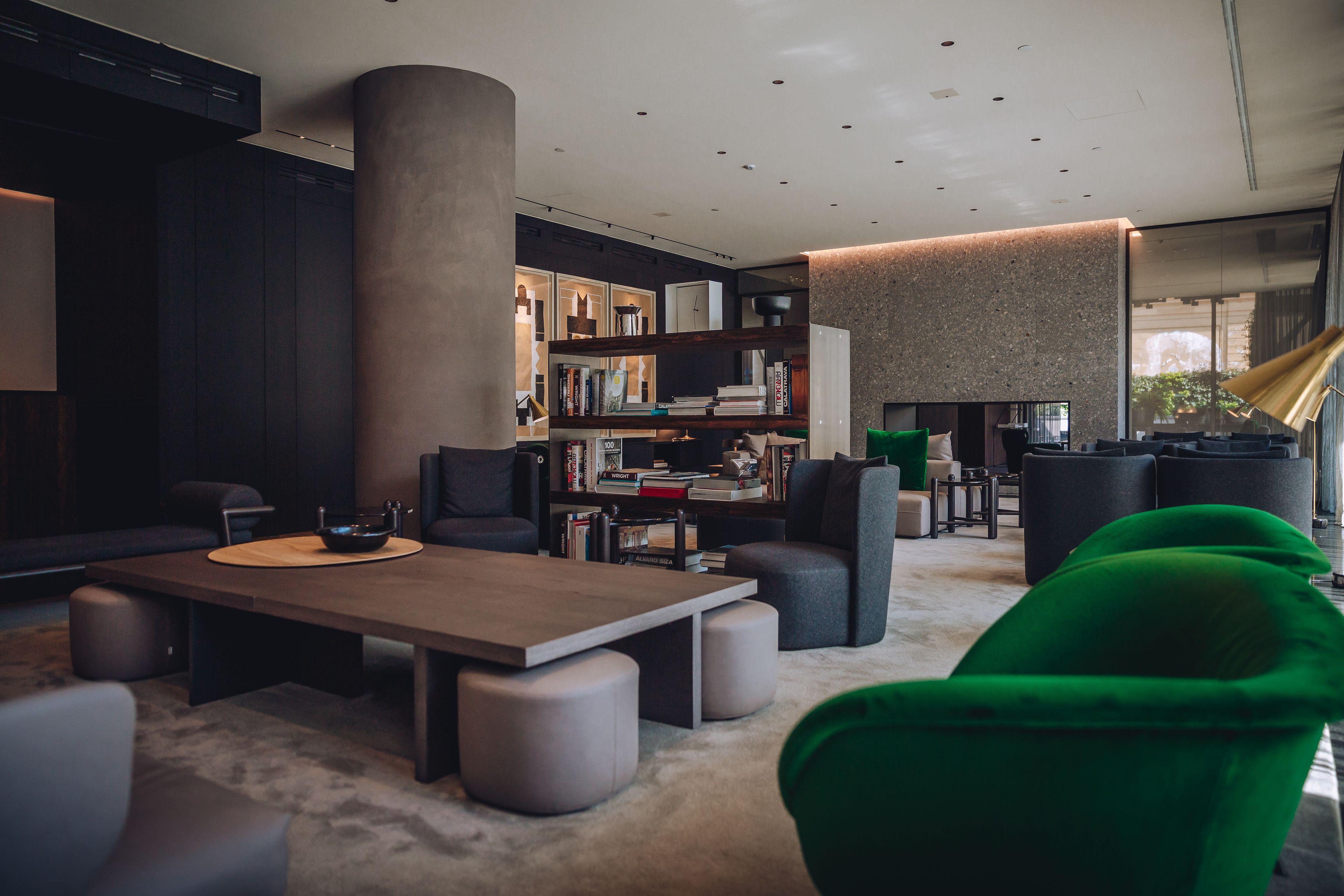 A modern living room with a large bookshelf, a fireplace, and a green armchair.