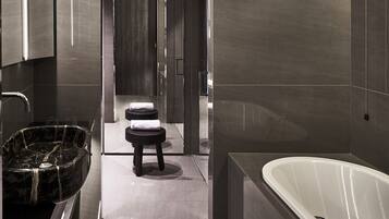 A modern bathroom with a large bathtub, a marble sink, and a small stool.
