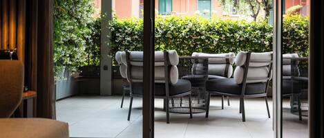 A modern outdoor seating area with wicker chairs and a glass door leading to a balcony.