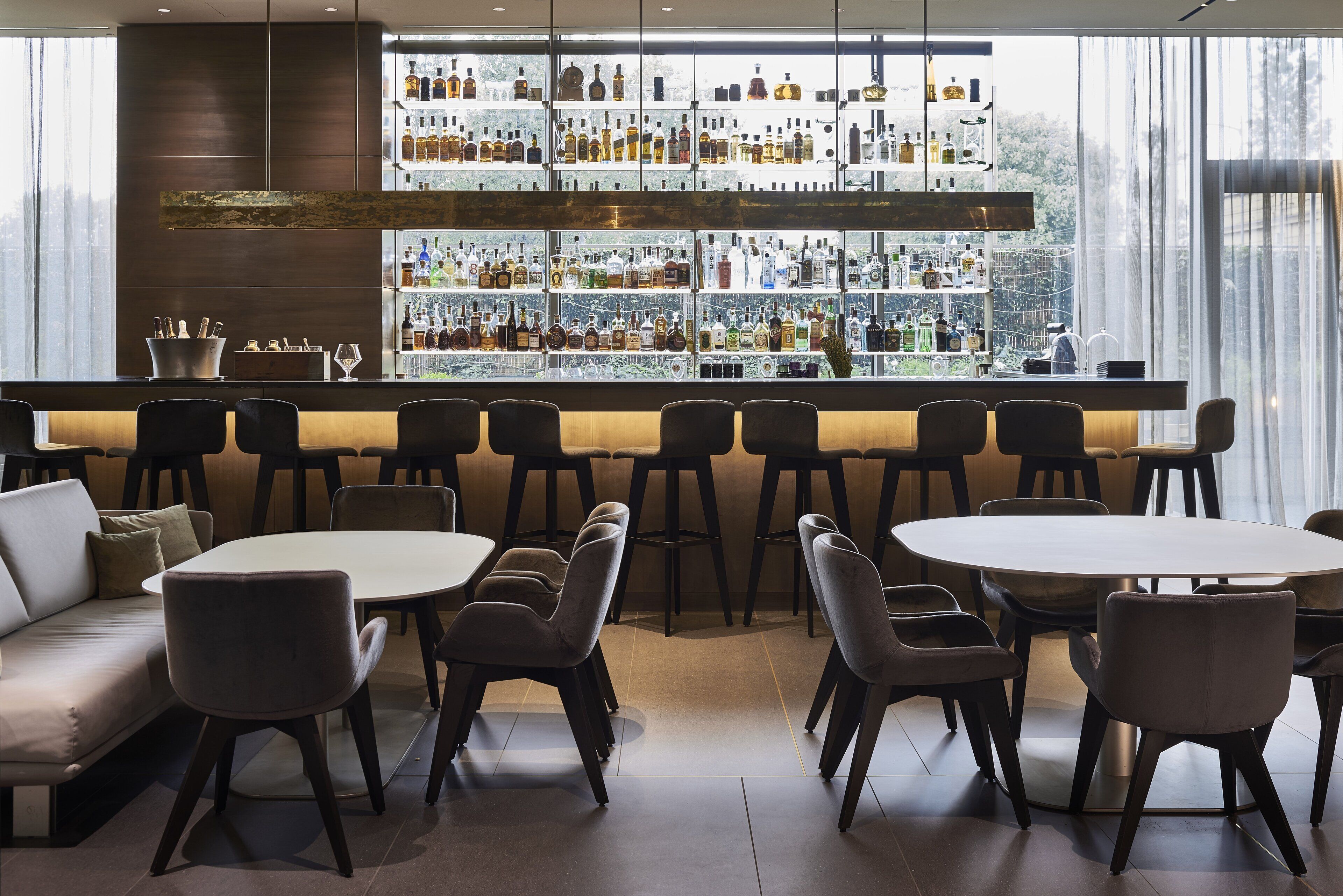 Un área de bar con diversas opciones de asiento, incluyendo una barra y varias mesas redondas con sillas.
