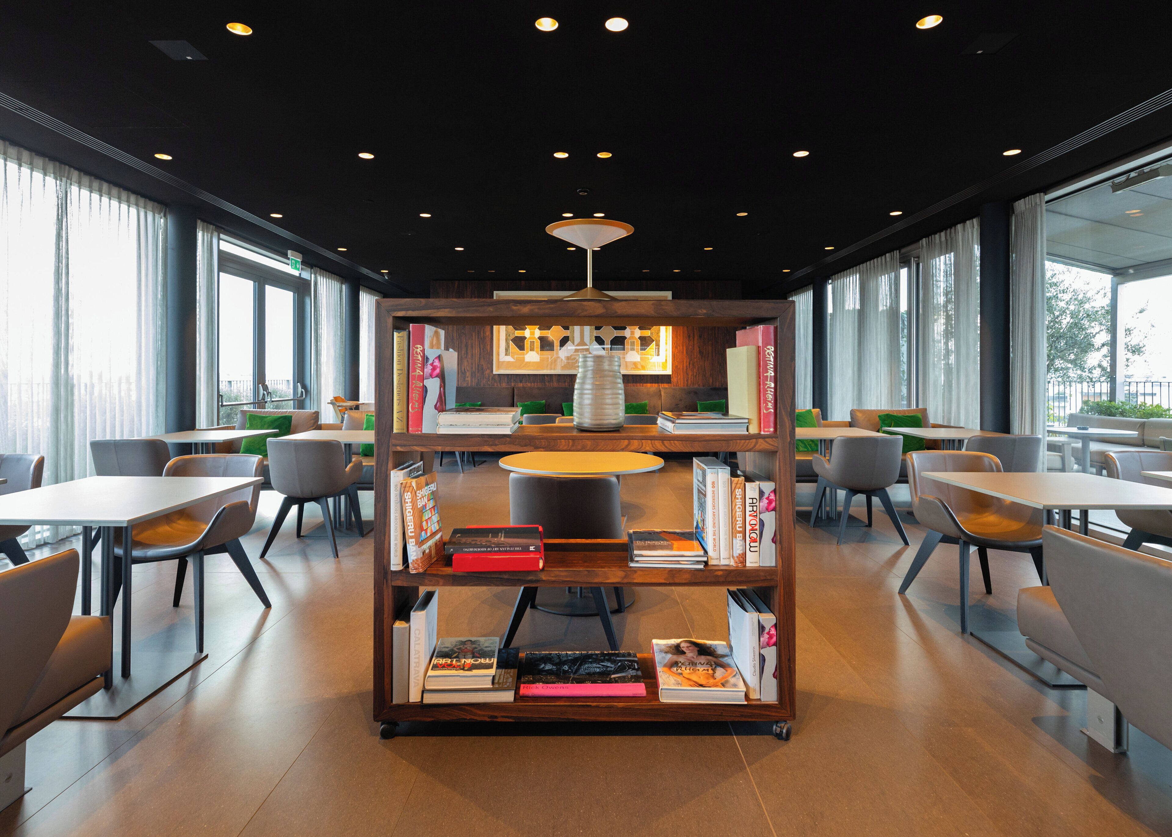 A modern library with bookshelves, tables, and chairs arranged for reading and dining.