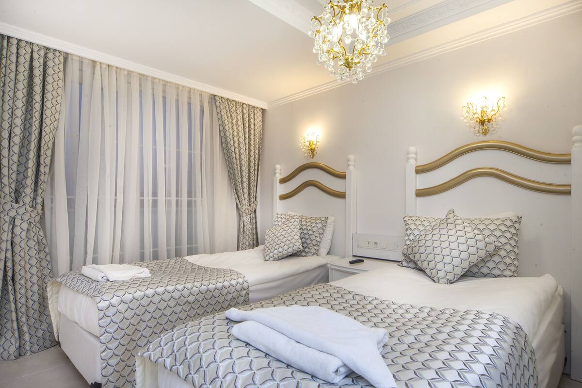 A hotel room with two beds, a chandelier, and patterned bedding.